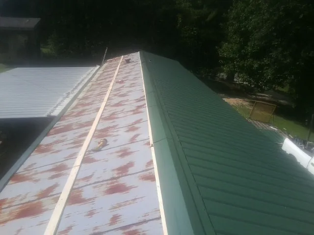 Old rusted panels beside newly installed green metal roofing — Wind Damage Roof Repair by Roofing Brothers in Pleasant Mount