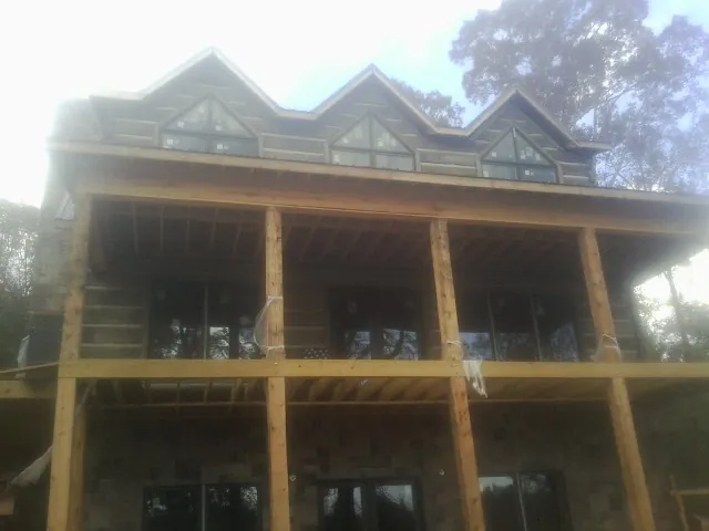 Dormers and porch framing on a large log home under construction — Roof Coating work by our crew in Pleasant Mount