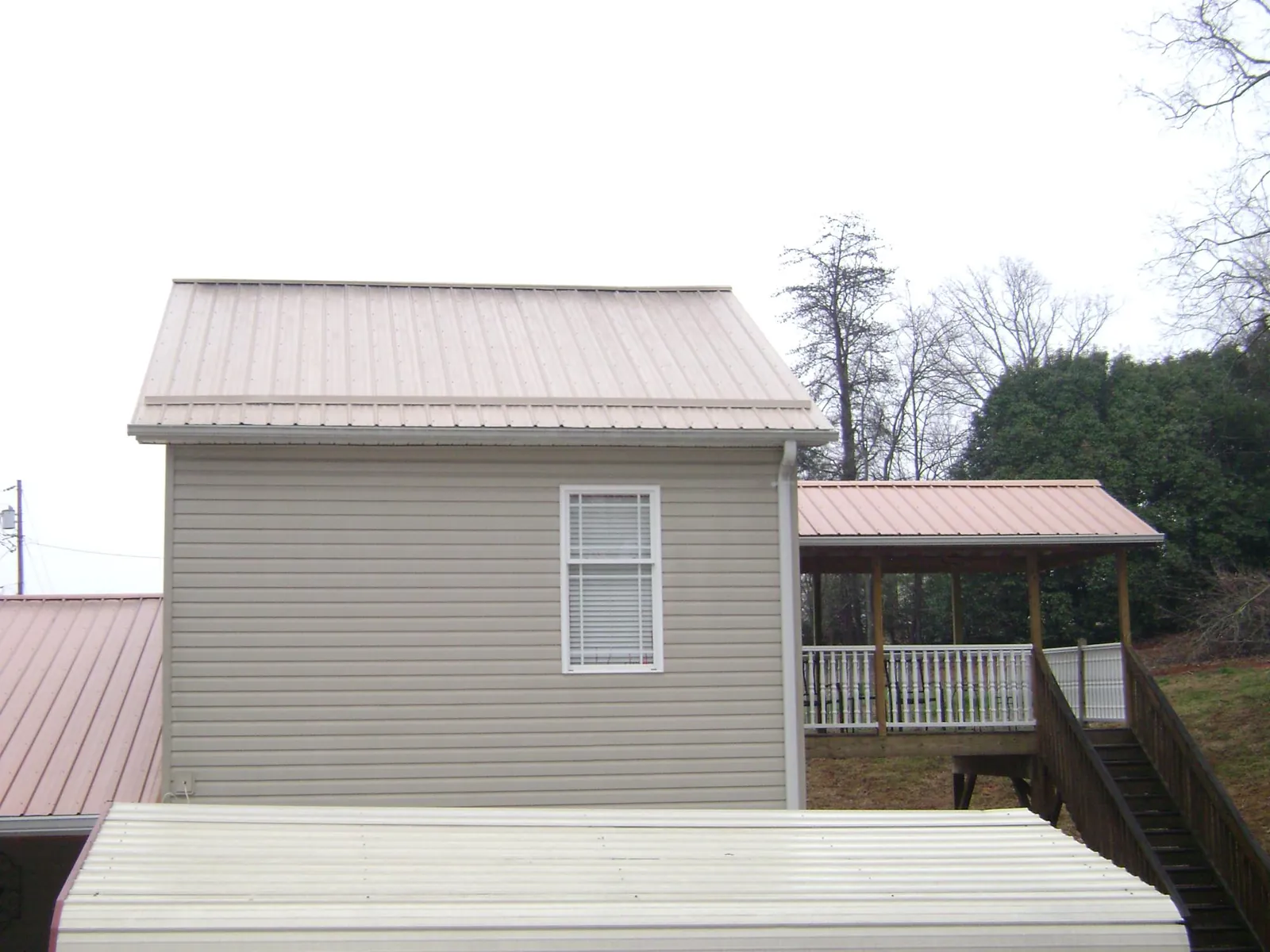 Tan metal roofs on a two story addition and attached porch, from a Roof Replacement job in Pleasant Mount