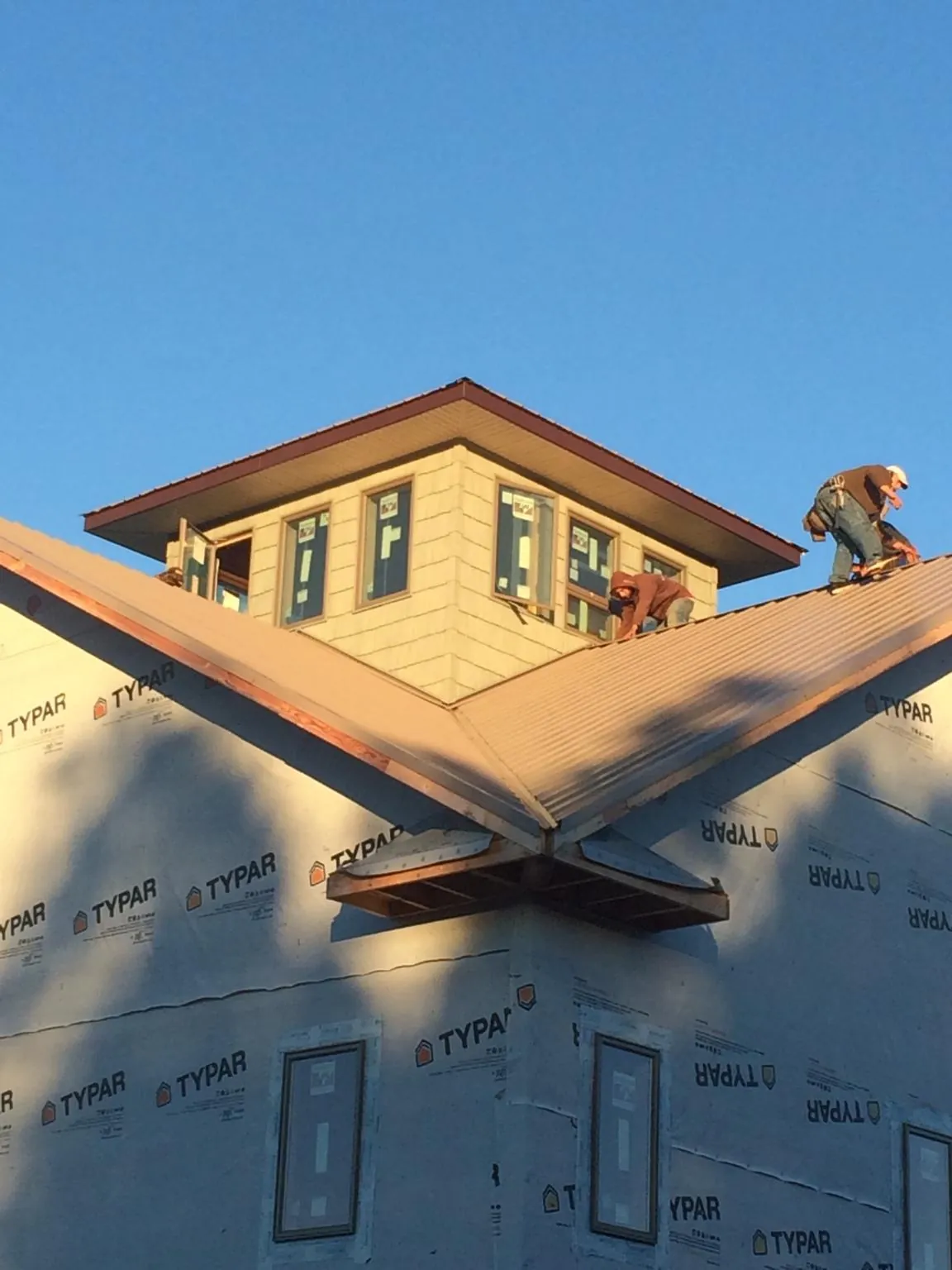 Roofers working around a rooftop cupola on a new metal roof at sunset — Roof Waterproofing in Pleasant Mount by Roofing Brothers